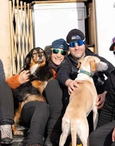 Aurélie et Rémy assis au soleil, un bras autour de deux de leurs Scandinavian Hounds