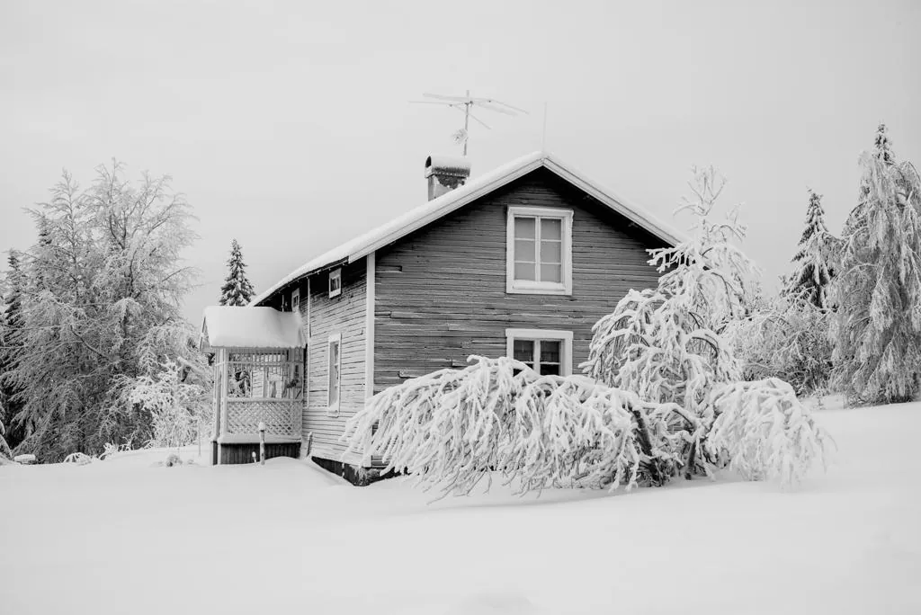 Chalet en bois enseveli sous la neige, entouré d'arbres givrés en plein hiver lapon