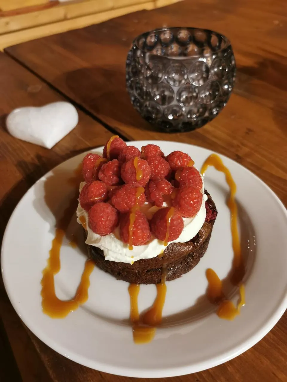 Gâteau au chocolat couronné de chantilly et de framboises fraîches, filet de caramel