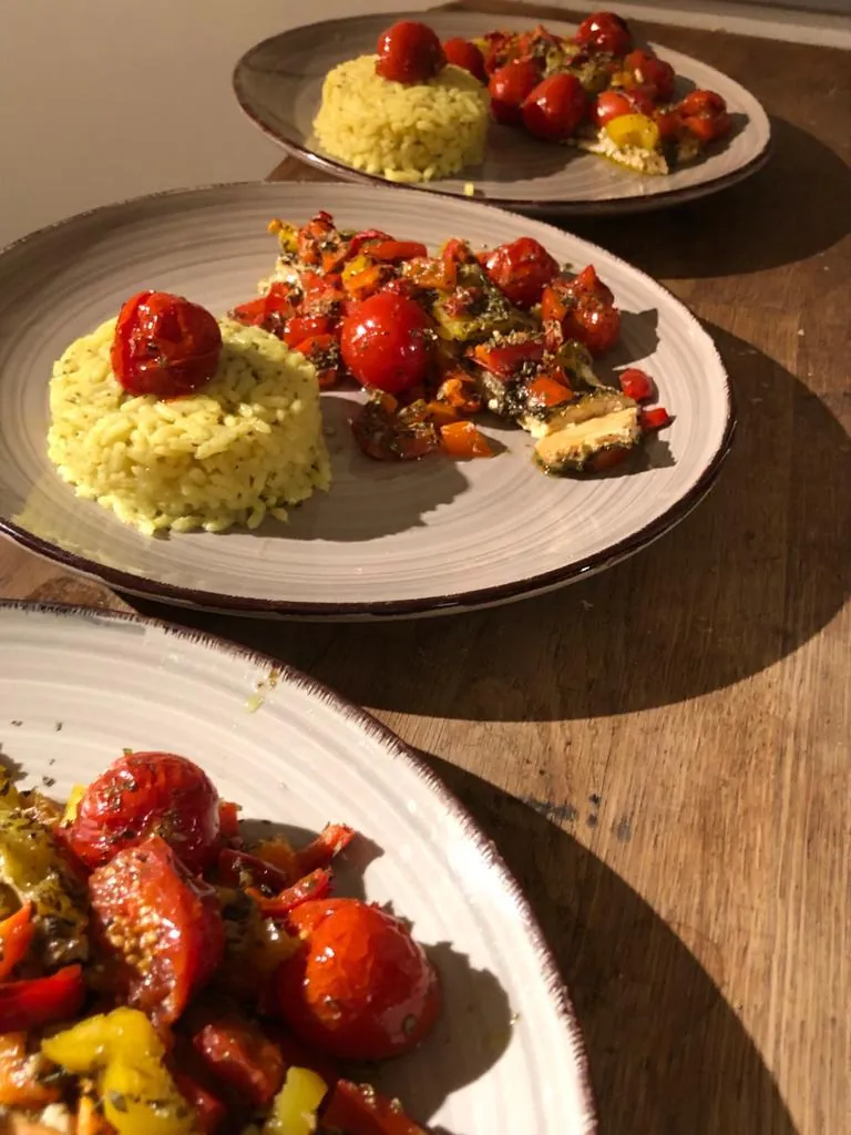 Assiettes dressées alignées sur la table en bois : riz safrané et poivrons confits